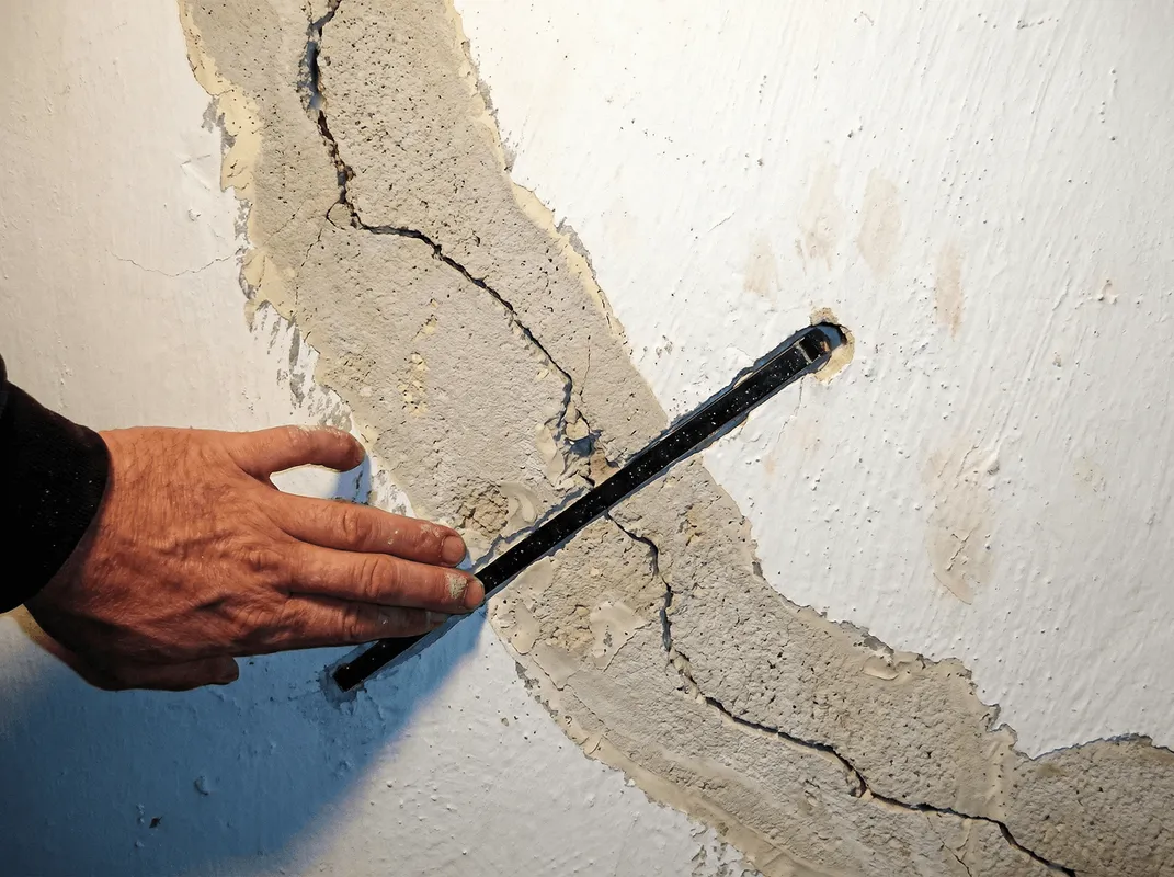 A wall with a large crack is being inspected by a professional in Buffalo, NY